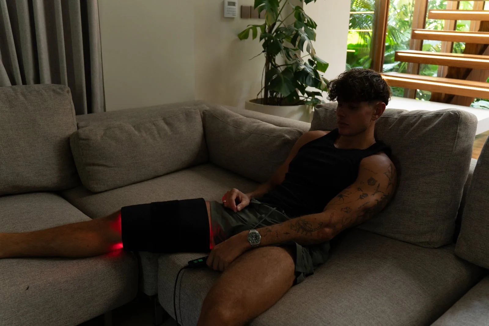 ThermoLab Auracell Pro belt wrapped around a knee and thigh with the controller in hand